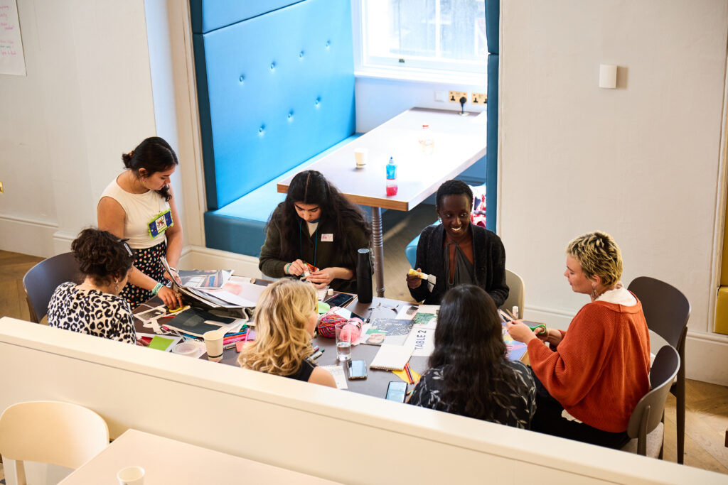A group of young people sat around a table, creating and in conversation.