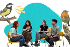 A group of four participants sitting in a semi-circle in front of a teal blob background with birds chirping on branches on either side