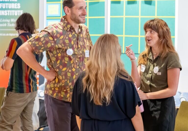 Three people engaging in a lively, collaborative conversation at a creative networking event.