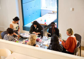 A group of young people sat around a table, creating and in conversation.