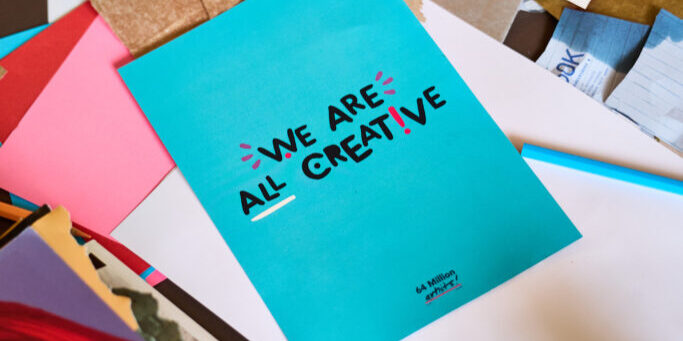A photo of a blue flyer that reads 'We are all creative'